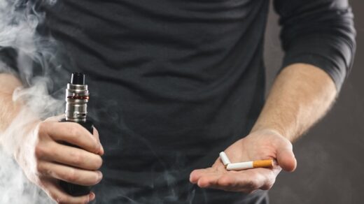 Man som håller i en vape och en cigarett