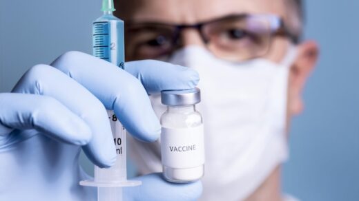 Läkare med munskydd, spruta och vaccin